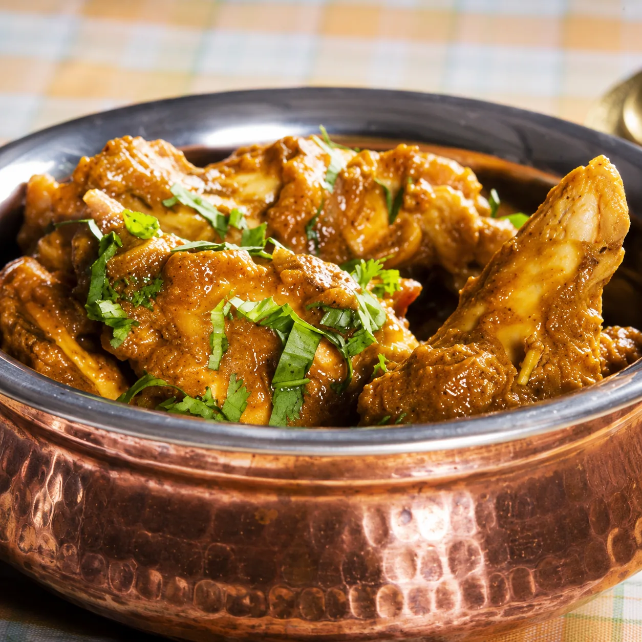 A rich chicken curry served in a copper handi